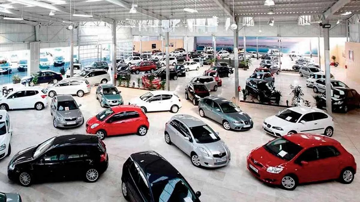 Salón de un concesionario con decenas de autos usados alineados bajo techo