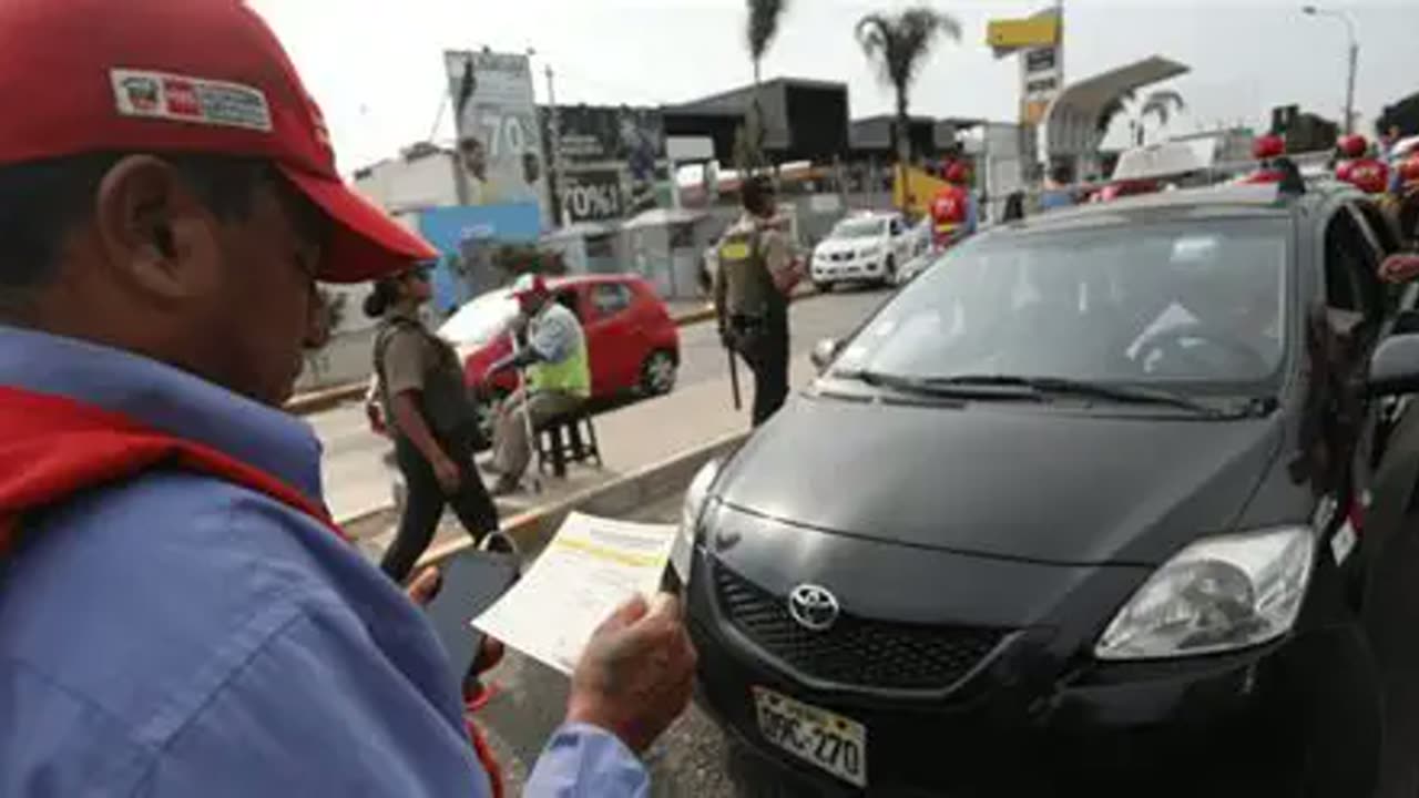 Un inspector con gorra roja toma nota junto a un auto detenido en la calle
