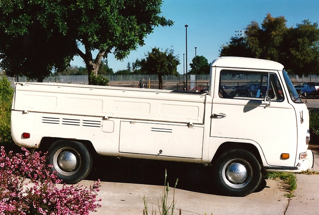 Camioneta antigua de color blanco estacionada junto a un jardín